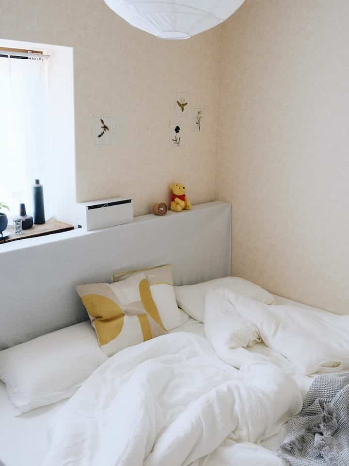 ベージュと白を基調にした寝室、黄色のクッションや小物がアクセントとなった落ち着きのある空間