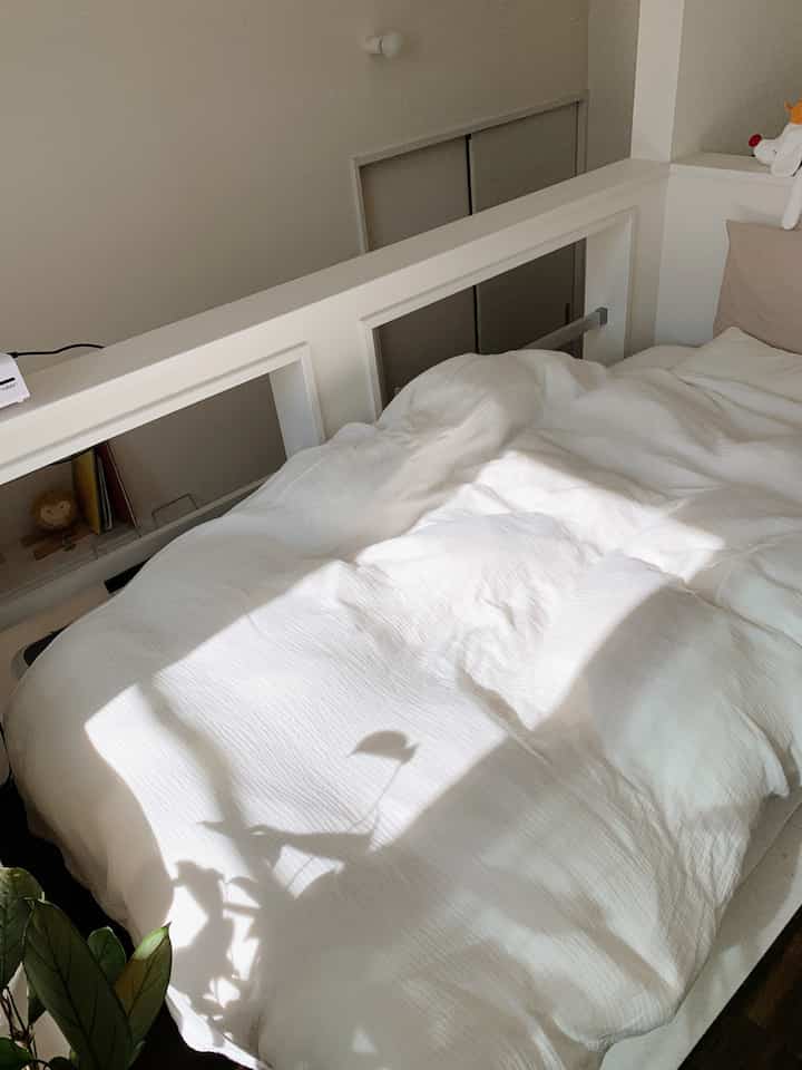 明るいホワイトとナチュラルトーンの寝室、リヨセルコットン二重ガーゼ掛け布団カバーと枕が置かれ、植物が自然な雰囲気を添える居心地の良いインテリア