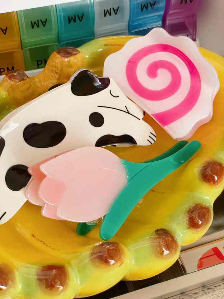 黄色いトレイの上に、犬の形とピンクの花のかわいいヘアクリップが置かれた雰囲気のある小物インテリア