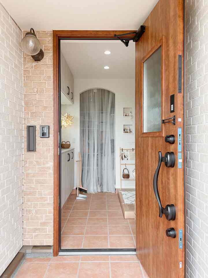 暖かみのあるブラウンとホワイトの色調の玄関、木製のドアとシューズラックが配置されたナチュラルな雰囲気のインテリア