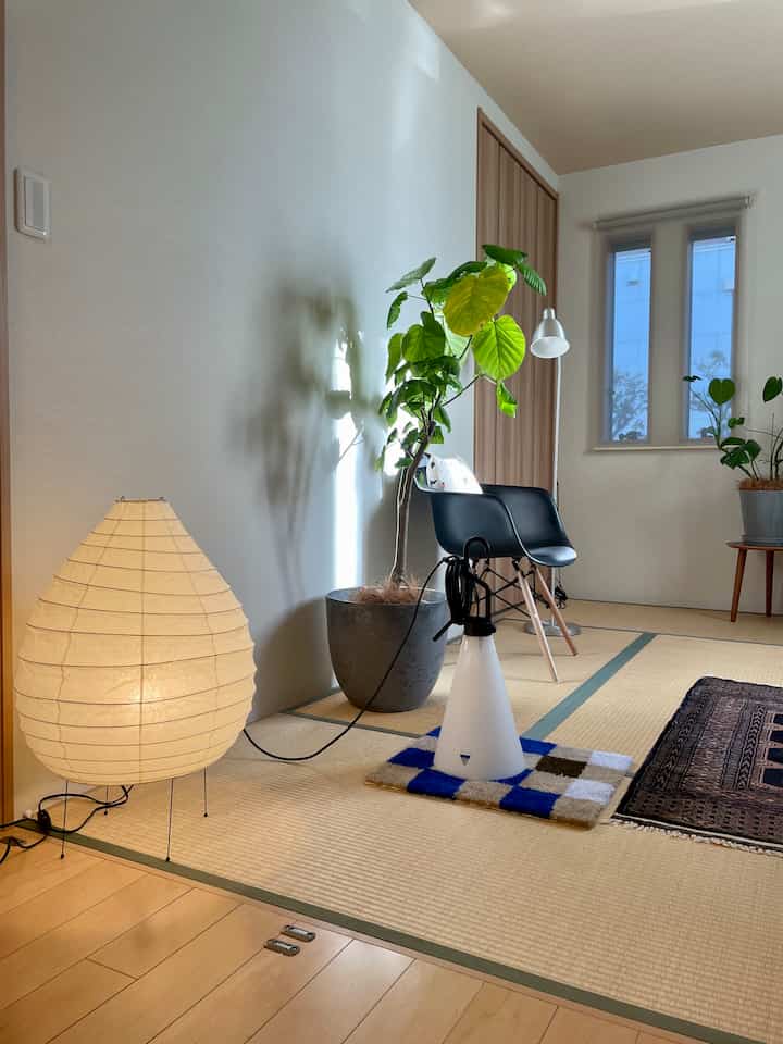 A 6-tatami Wa-Modern Japanese room with white walls, light brown flooring, featuring floor lamps and plants in a simple interior setting