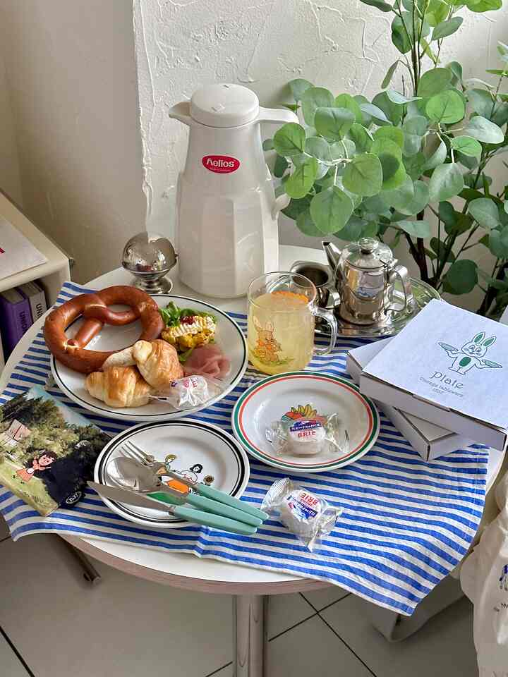 白と青のトーンの丸いダイニングテーブルにキャラクターイラストの皿やグラス、ペストリーが置かれた雰囲気あるキッチンのインテリア