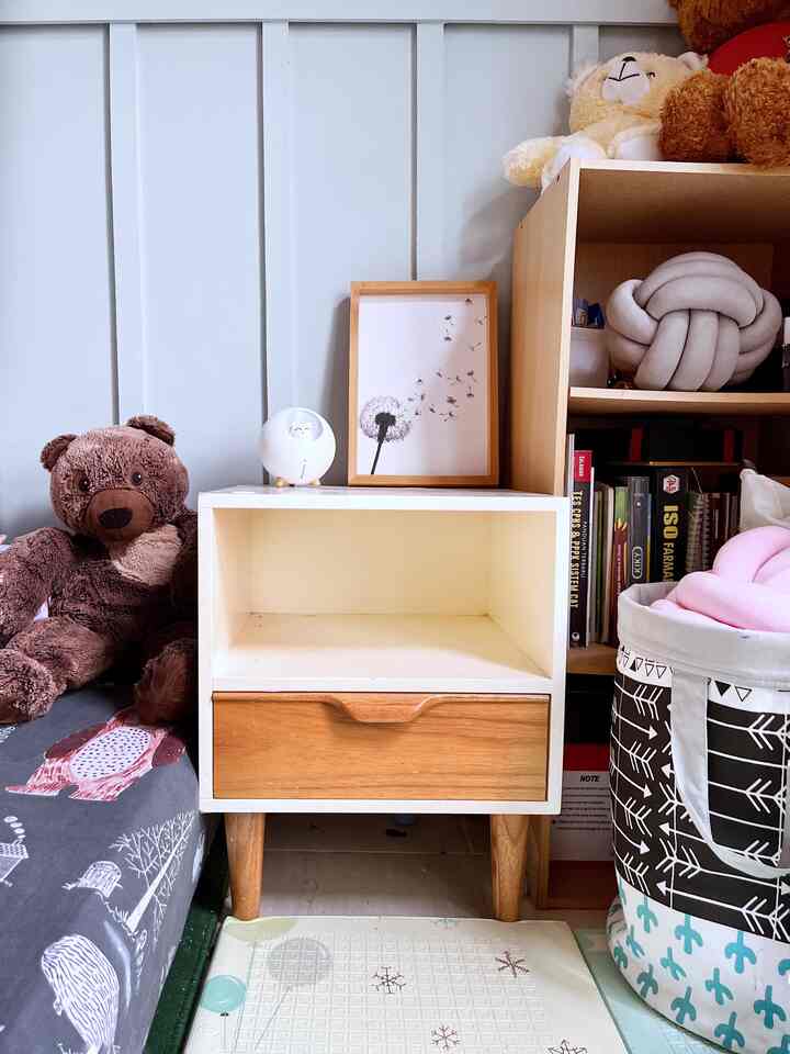 White and wood tone kids' bedroom featuring a nightstand and toy storage, creating a cozy and warm atmosphere