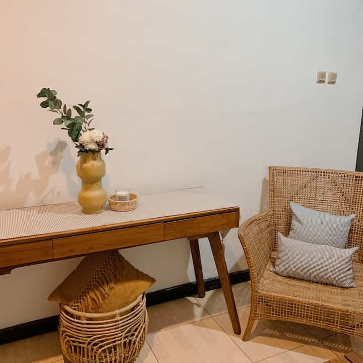 Natural wood tone and beige entrance space featuring rattan furniture, a vase, and candle with a clean atmosphere