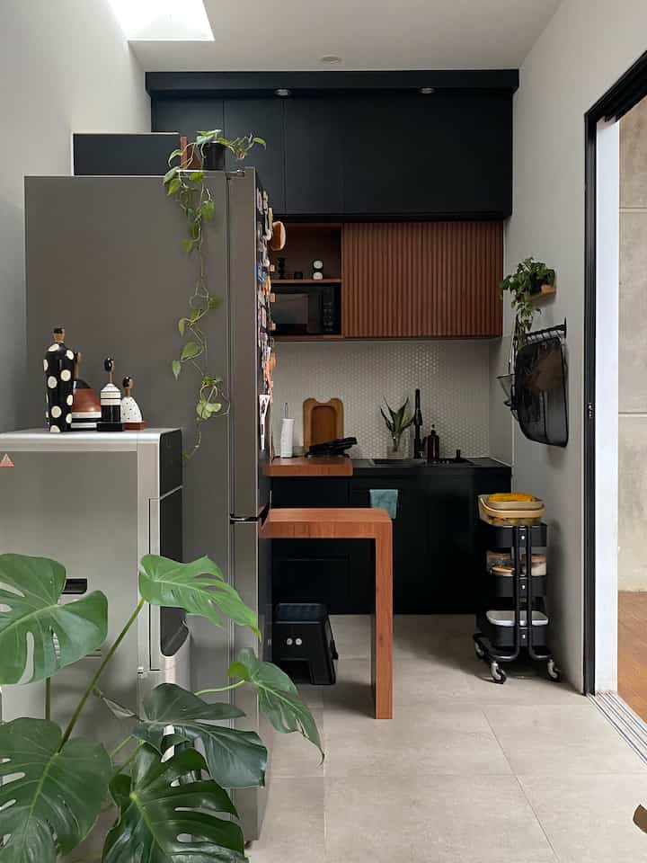 Mid-Century Modern kitchen with wood tones and black cabinetry, slim space featuring storage ideas and a bright atmosphere