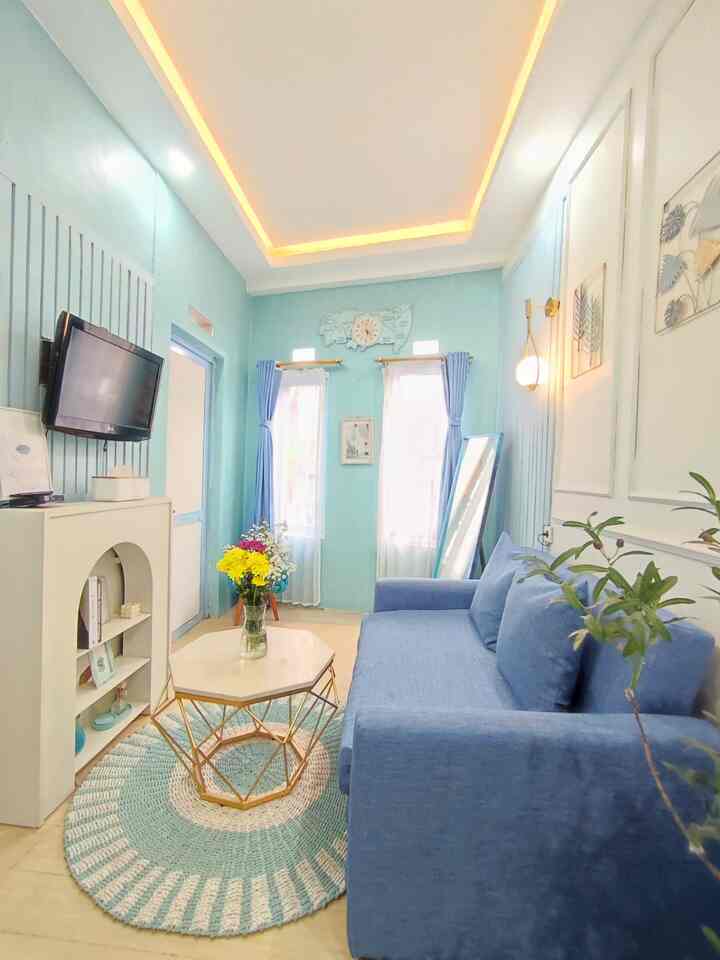 Cozy 4m by 2.3m living room featuring bright blue walls and sofa with round woven carpet and warm ceiling lighting