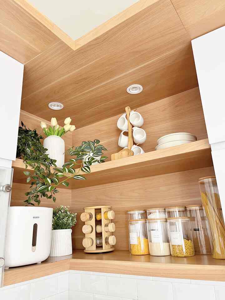 Natural kitchen with white and wood tones, featuring organized storage and plants creating a clean atmosphere