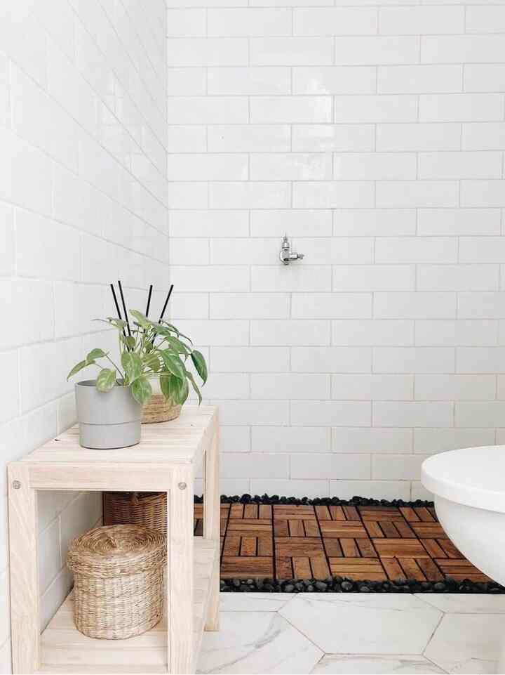 White tiled bathroom with natural wood-tone furniture creating a compact, serene space