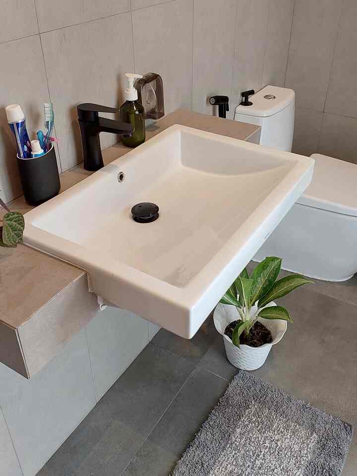 A bathroom in white and black tones featuring a semi recessed sink and black faucet, creating a minimal and modern atmosphere