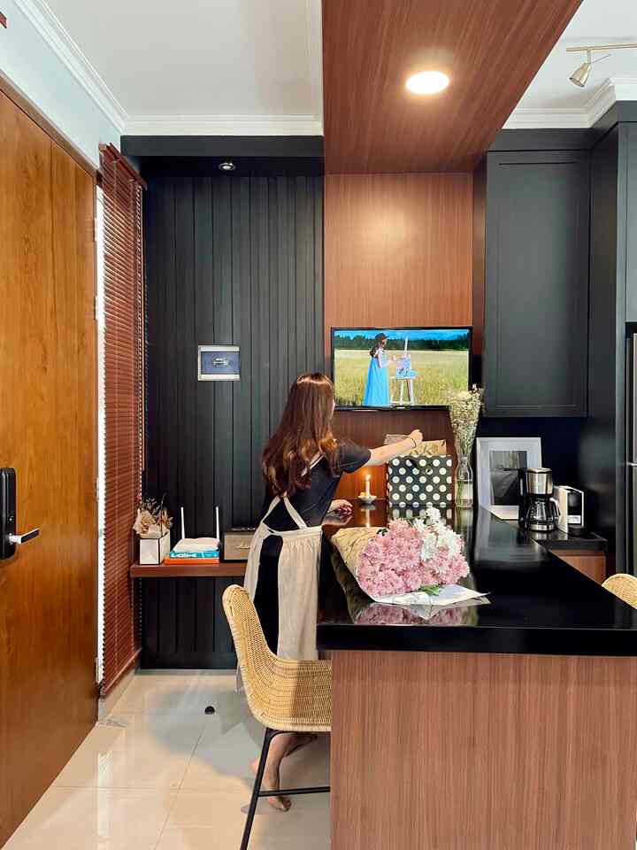 Tempat berkumpul bersama keluarga biasanya ada di Living Room yang nyaman dengan dikelilingi sofa, akan tetapi di rumahtuju ini, kami lebih sering menggunakan meja makan untuk kegiatan berkumpul atau sekadar mengobrol.

Saya memadukan dua warna yakni warna natural dari elemen kayu dan material-material warna hitam untuk focal point dari desain area living ini. Ambiance/mood warna dari kayu menghilangkan kesan kaku dari warna hitam sekaligus memberi nuansa hangat di area living dan sekelilingnya. 

Karena keterbatasan lahan, dan menyesuaikan dengan kebutuhan ruang sehingga dari awal saya memutuskan untuk membuat meja makan yang panjang secara custom, supaya kesan lebih lapang dan lebih banyak kegiatan bisa ditampung di meja makan.
Untuk meja living sekaligus sebagai meja makan ini, saya menggunakan warna hitam supaya membersihkannya lebih mudah. Sementara bagian dinding ditutup panel dengan aksen vertical, dan diberikan ambalan kayu sehingga saya bisa menambahkan hiasan dekorasi dried flowers, table lamp, maupun speaker untuk pelengkap TV. Supaya saat berkumpul kami bisa menonton TV, maka panel TV sengaja dibuat menyatu dan menerus ke panel ceiling meja makan.

#livingroomstyling
#livingroomdecor
#livingroommakeover
#homestyling
#warmcolor
#personalizedfurniture
#moderncontemporary