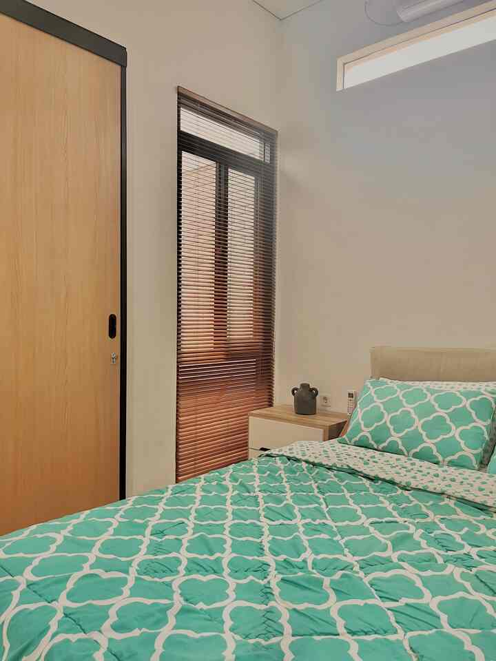 Natural-toned bedroom with wood sliding door and wooden blinds, featuring a simple and calming Japandi style