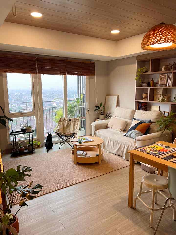 A warm living room with wood tones and white, featuring a cream sofa and khaki camping chair in a cozy setting