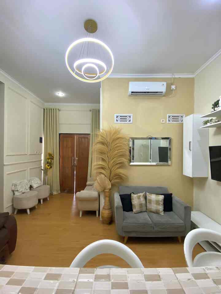 Minimal living room with light brown wood tone flooring and gold pendant lighting as focal accents
