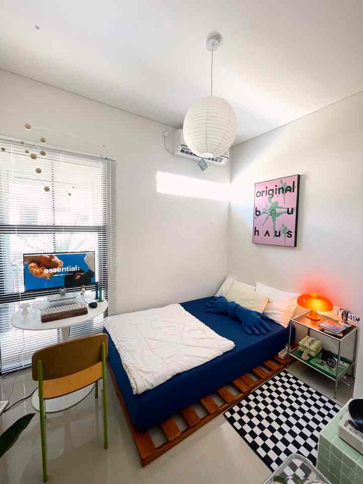 Mid-Century Modern small bedroom with white walls and blue bedding, featuring a nightstand with an orange table lamp