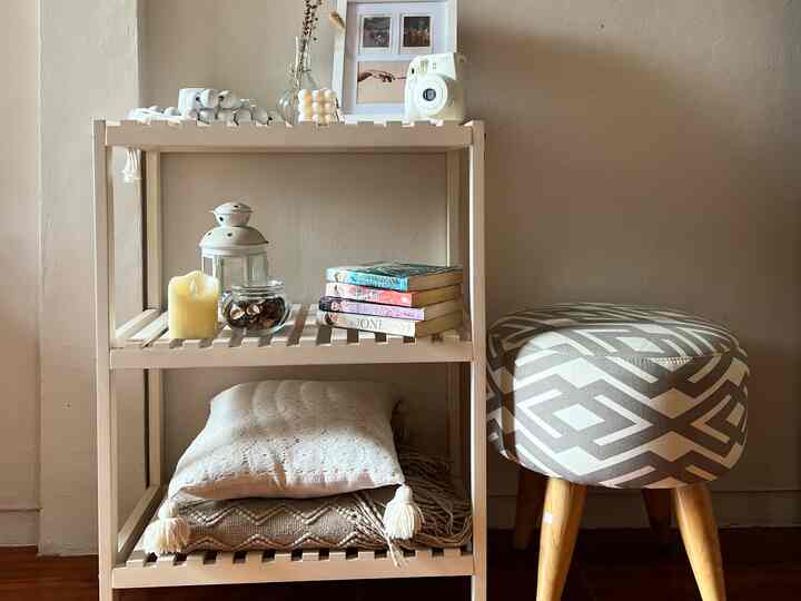 A cozy natural kids' room with beige tones featuring a wooden rack and patterned stool