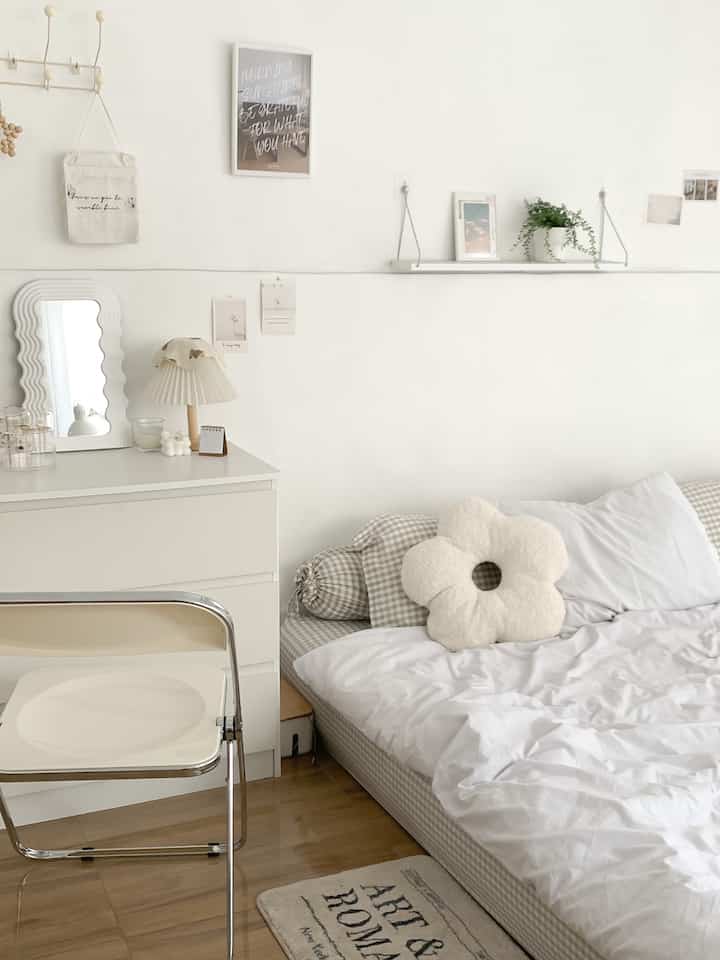 White and natural wood-toned bedroom featuring a simple sofa bed with cushions, dresser, and a wavy mirror in a cozy setting