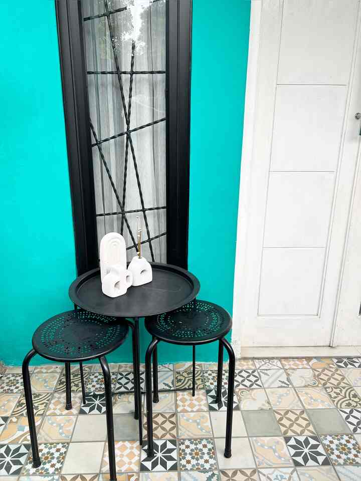 Turquoise wall balcony featuring black side table and stools with patterned tile floor
