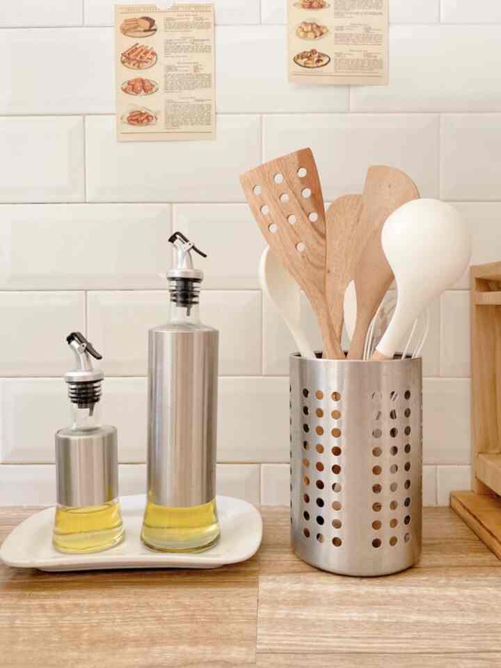 Natural tone kitchen featuring white tiled wall and wooden kitchen utensils arranged neatly, creating a clean atmosphere