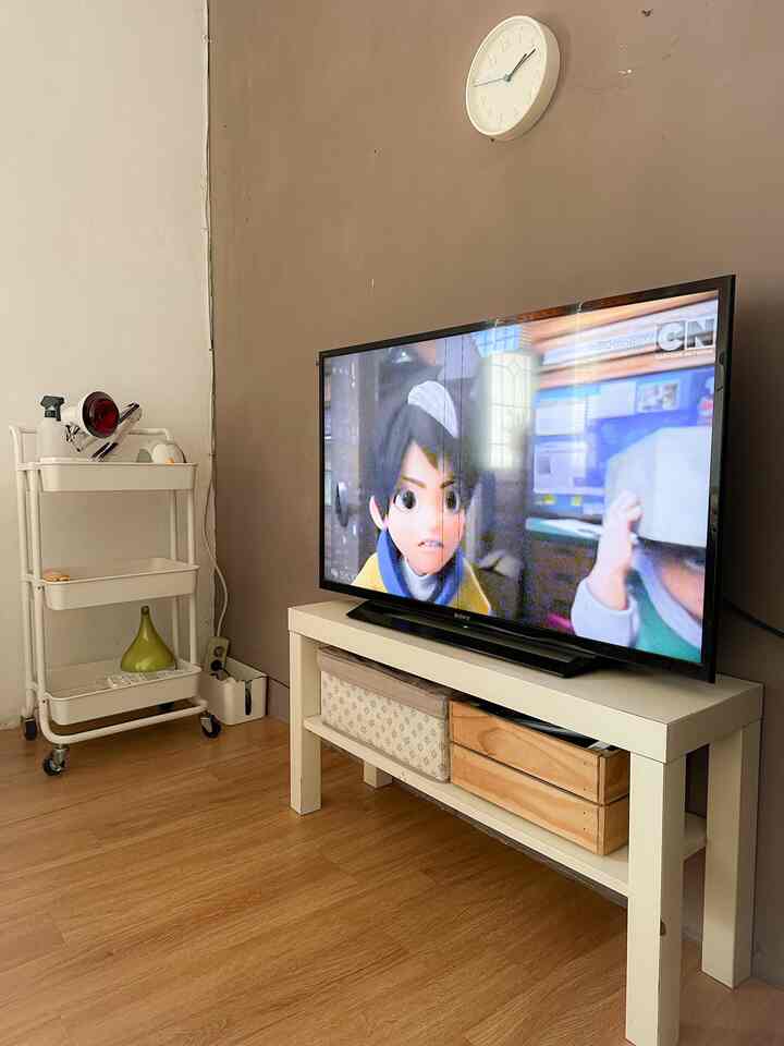 Natural beige and white walled kids' room with wood tone flooring featuring TV and white TV stand creating a cozy space