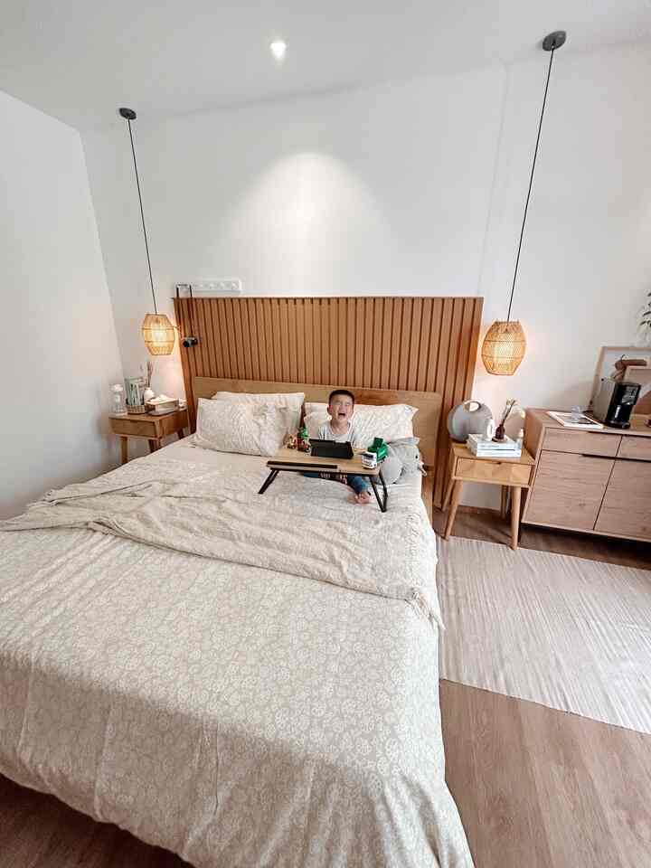 Beige-toned natural wood bedroom featuring a child sitting centrally on the bed, creating a cozy atmosphere
