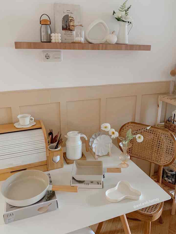 Natural color and white toned kitchen featuring dining table with neatly arranged kitchen utensils and plates, cozy atmosphere