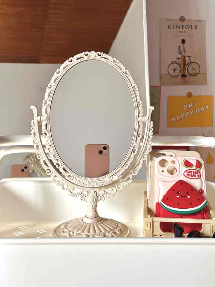 White-toned small room featuring a decorative oval mirror and a movable trolley storing skincare and cosmetics, creating a neat space
