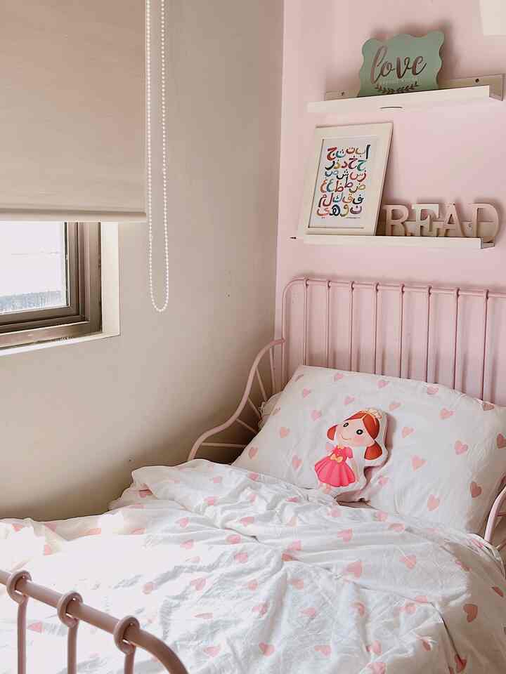 Pink and white toned kids' room featuring heart-patterned bedding and pink bed frame in a cozy small bedroom
