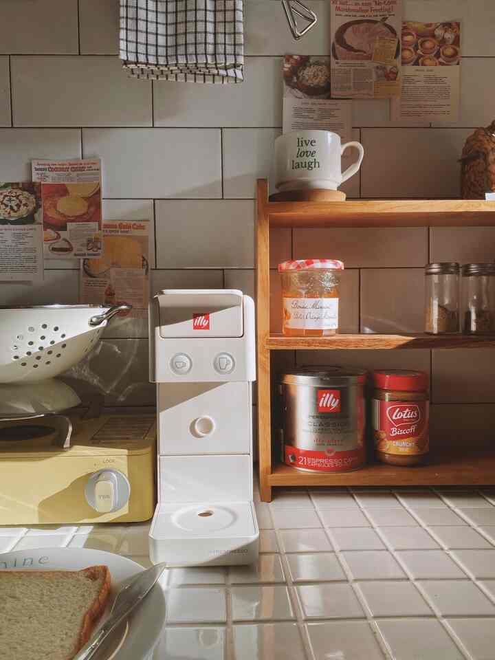 Cozy kitchen space with warm natural sunlight, white tiles, and wooden tone shelves