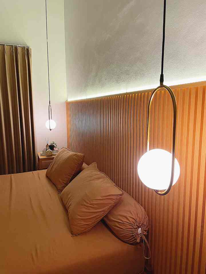 Cozy bedroom featuring warm brown wood tones, bed, and pendant lighting creating relaxing atmosphere