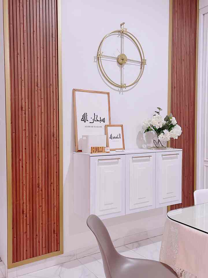 White and brown toned dining room featuring wall clock, framed art on floating cabinet, and a vase with flowers creating a neat atmosphere