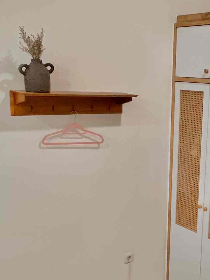 Minimal bedroom with white walls, wood tone closet and shelf, showcasing simple and natural Japandi style interior