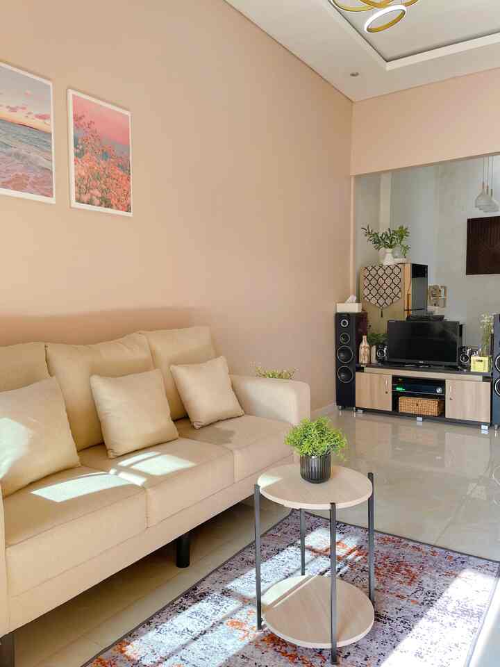 Soft pastel-toned walls and natural beige sofa with a round coffee table in a compact living room space