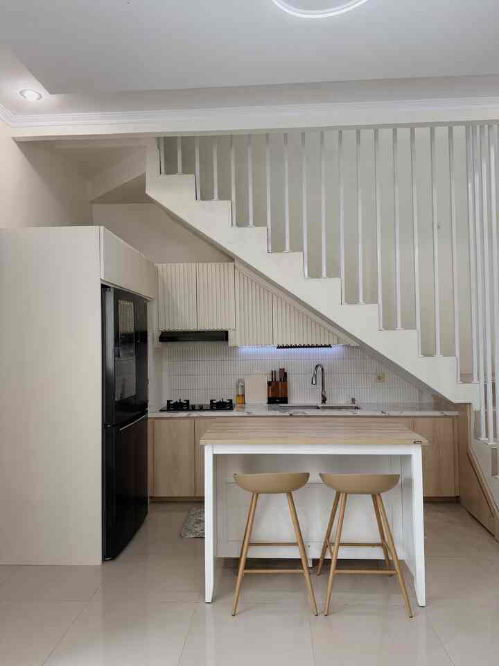 White and beige toned kitchen featuring cabinets under stairs and bar stools, simple and modern atmosphere