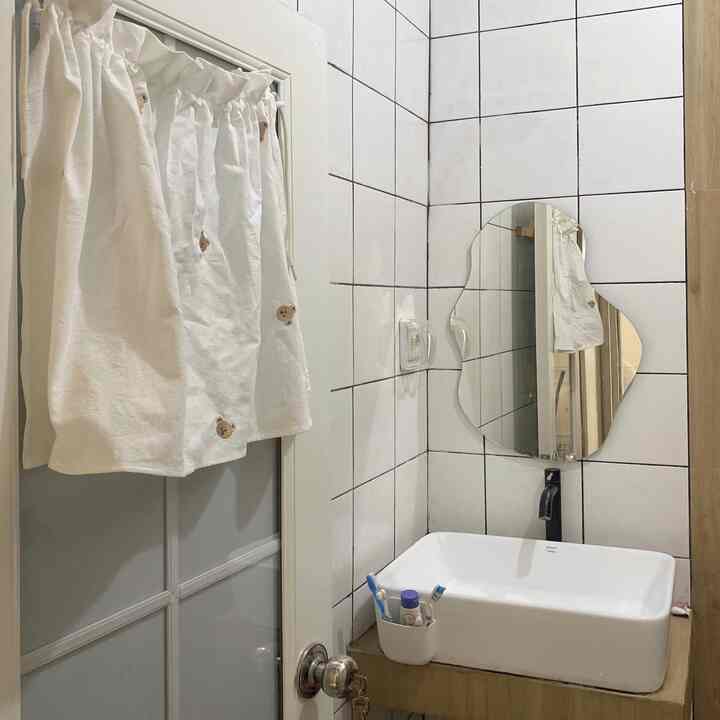 White and beige toned small bathroom featuring bear pattern curtain and uniquely shaped mirror in a kid-friendly setting