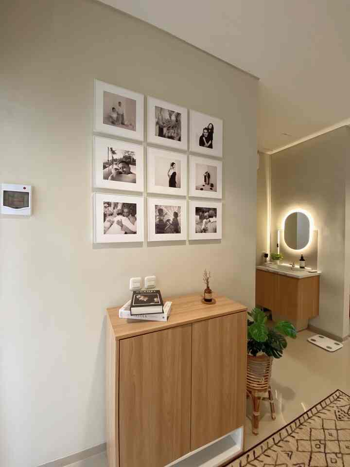 Natural-colored small bathroom space featuring wood tone cabinet, wall art, and illuminated minimal style interior