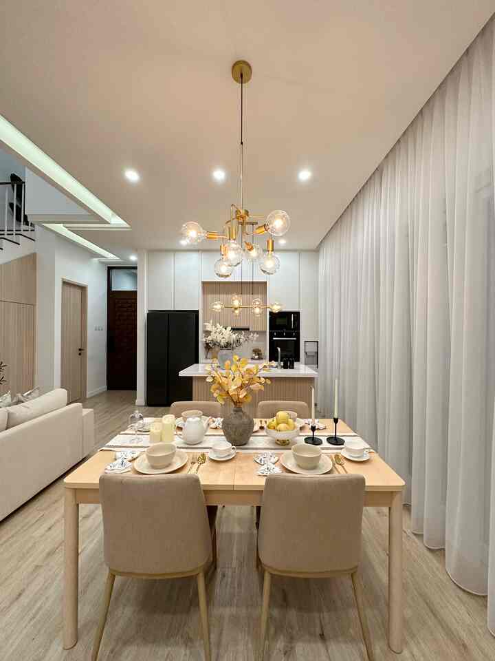 Bright wood tone and white dining room and kitchen featuring a central dining table and chairs in a modern Japandi style space