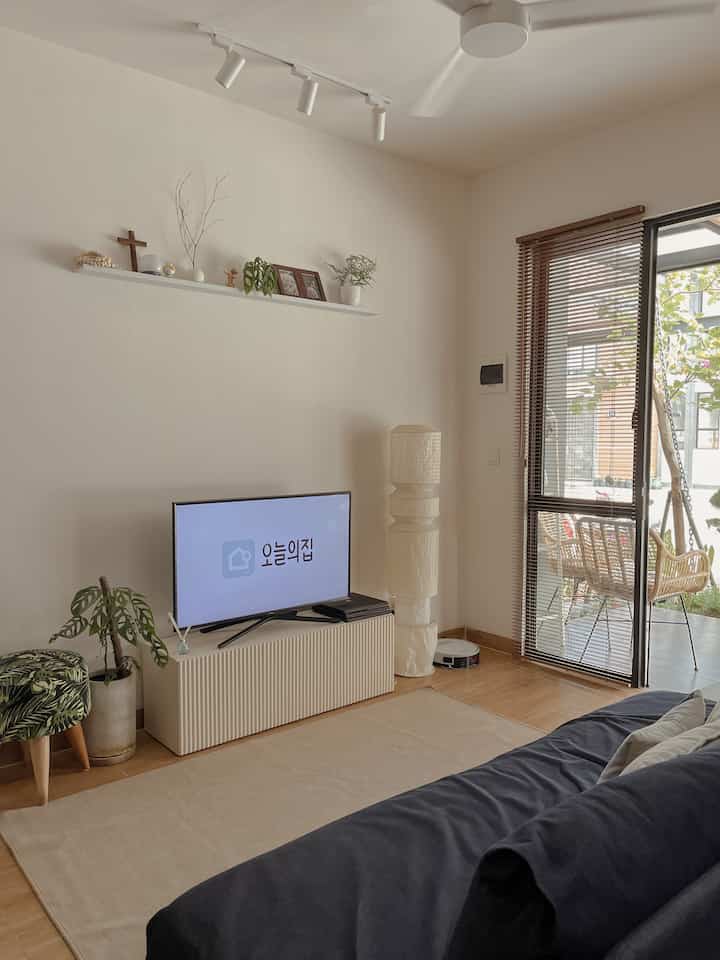 Ivory-toned living room featuring a navy sofa, plants, and natural light creating a simple cozy atmosphere