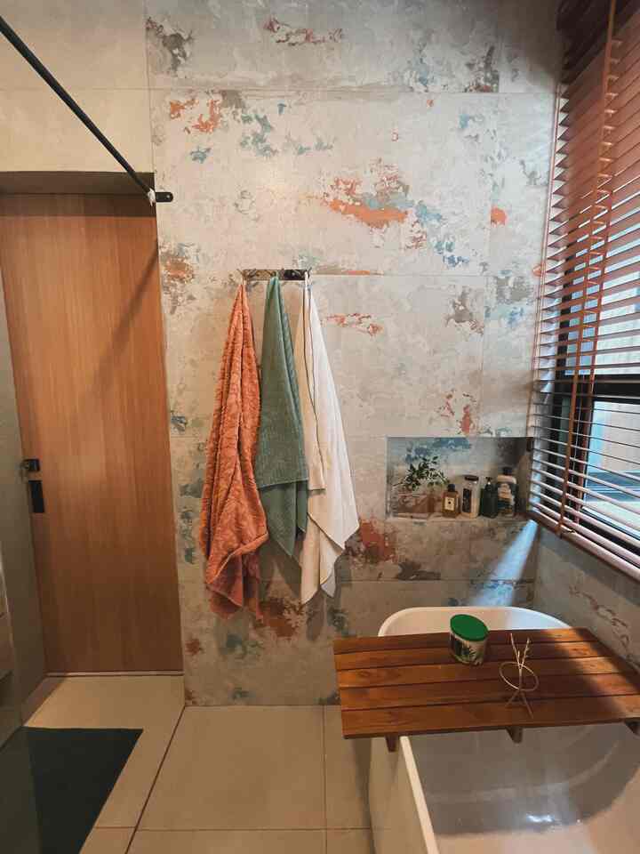 White and wood tone bathroom featuring decorative tile wall and three towels in a modern industrial setting