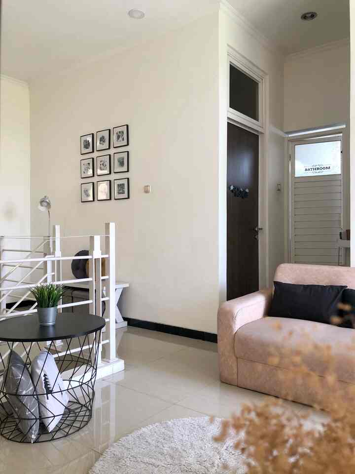 A small living room dominated by white and beige tones, featuring simple wall decor and natural-colored furniture creating a cozy atmosphere