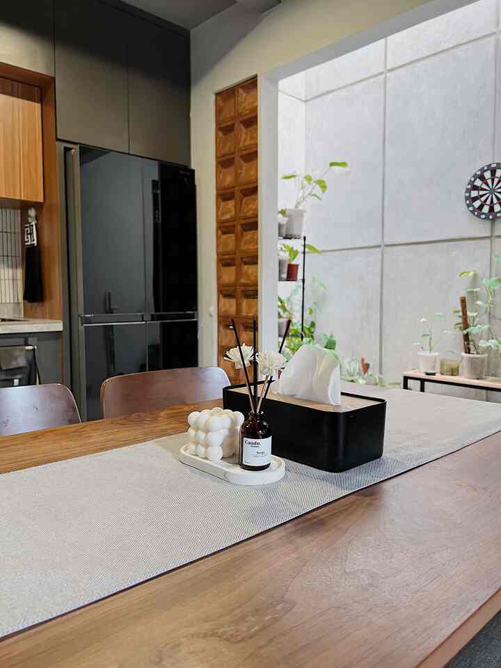 Natural wood tone and black accented kitchen dining space with plants and table decorations creating a cozy atmosphere