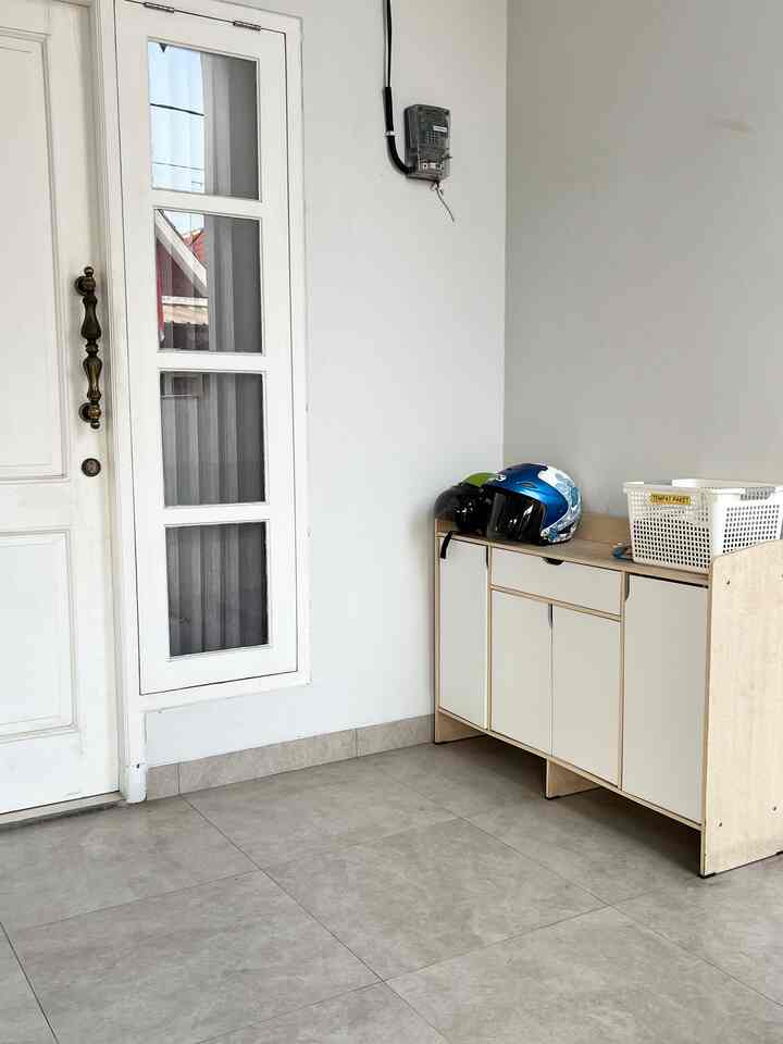 Clean entrance with bright white walls and beige floor, featuring a shoe cabinet on the right side