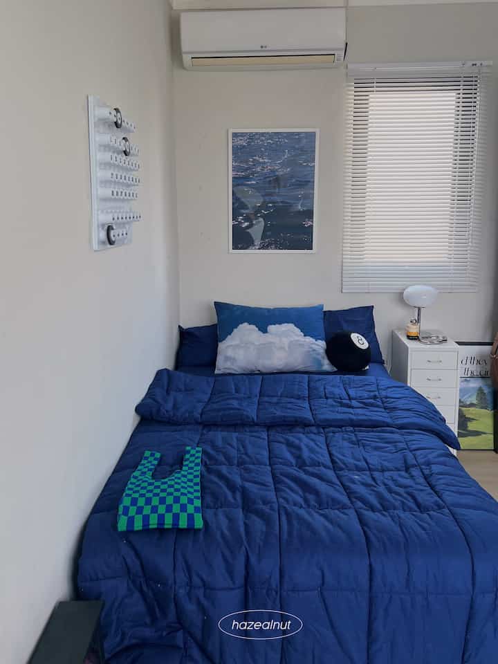Navy blue toned bedroom featuring a central bed with white side drawers in a neat compact layout