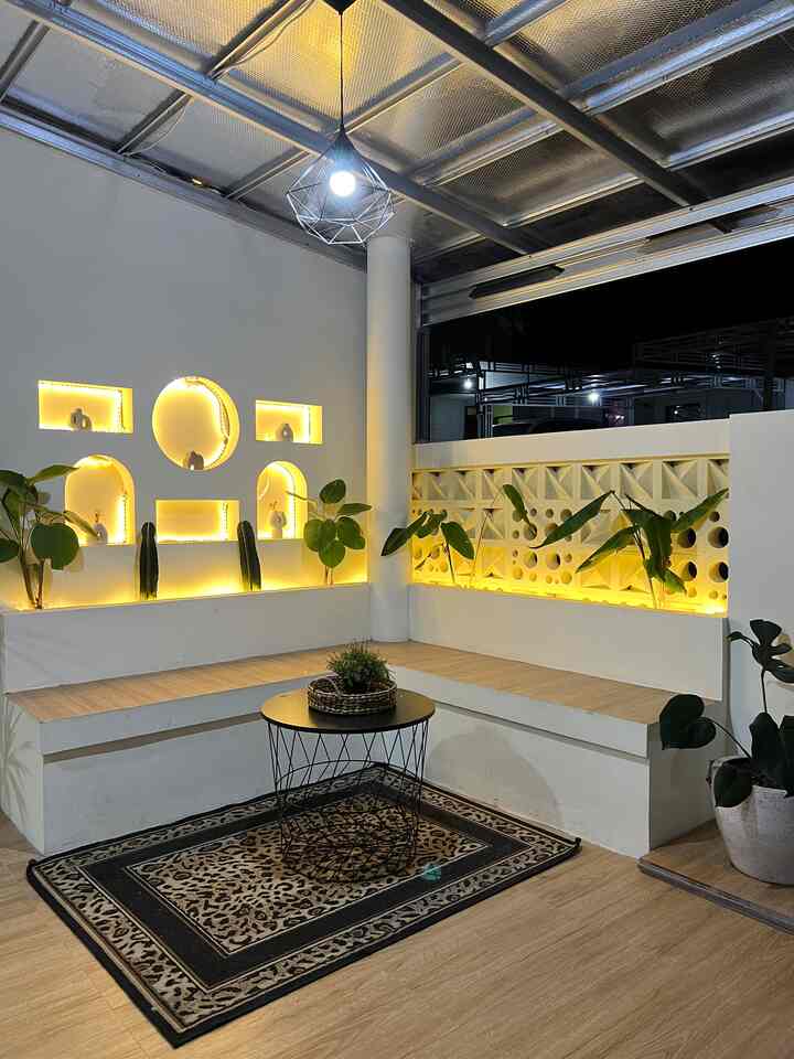 Warm-lit white bench seating with plants in a cozy cafe-style balcony space at night