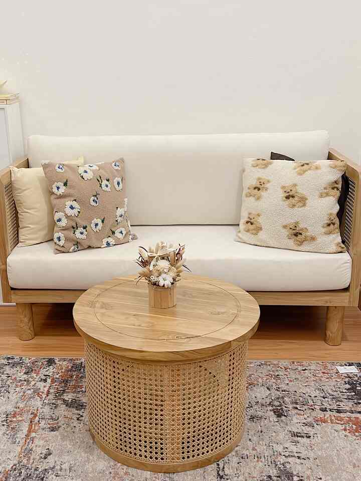 Natural modern living room with harmonious white and wood tones, featuring a rattan coffee table and sofa adorned with floral cushions