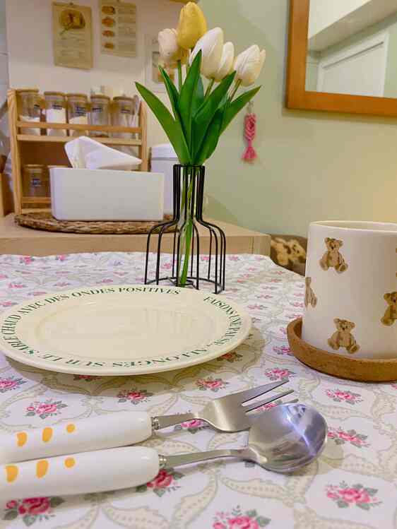 White and pastel toned dining room featuring a vase with tulips and a cute teddy bear cup on a cozy table setup