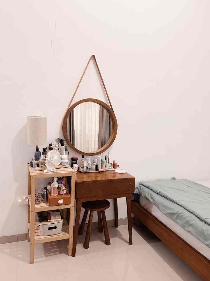 Natural bedroom with white walls and floor, wood tone vanity and shelf, and a cozy bed arranged neatly