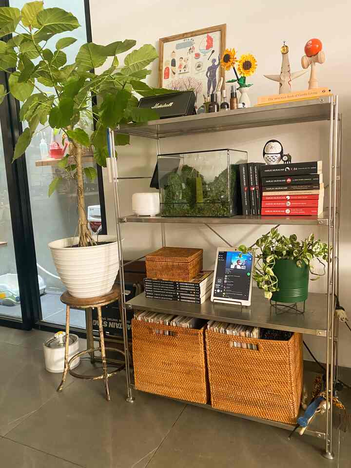 Green and brown toned space featuring plants, terrarium, and basket storage in a cozy living room corner