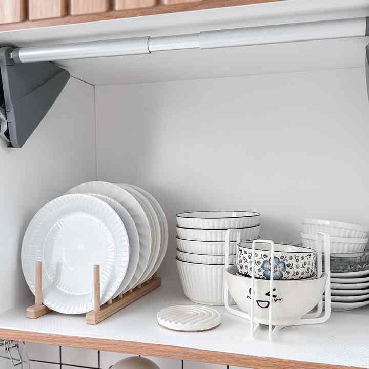 White and natural color kitchen storage area featuring neatly arranged plates and bowls with a clean, organized atmosphere