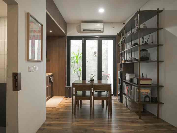 Natural wood tone and white dining room featuring a central dining table and shelving, creating a warm atmosphere