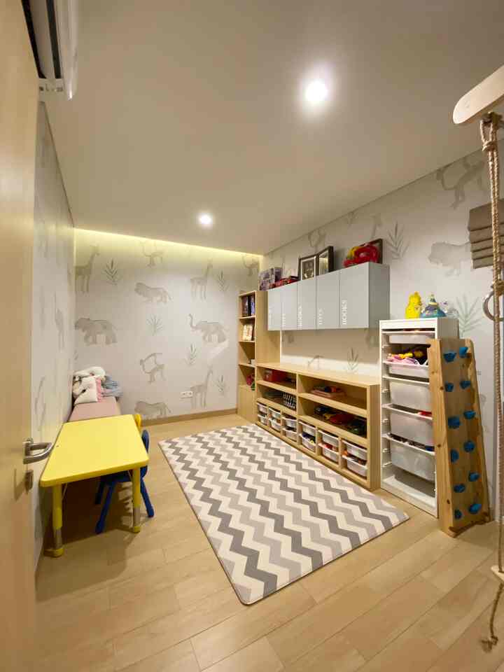 Bright wood tones with gray and white animal wallpaper in a kids' room featuring a yellow child desk and multiple storage units creating a neat, cozy space